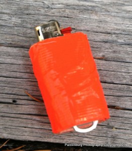 Add several feet of duct tape and a poptop to a standard BIC mini lighter and you have a firestarting kit. Secure the lighter to a lanyard with the poptop.
